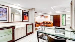 A modern living room with a glass dining table, leather sofas, and artwork on the walls. - Treebo Saga Apartment (Bengaluru)