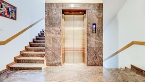 A marble staircase leading to an elevator on the first floor. - Treebo Saga Apartment (Bengaluru)