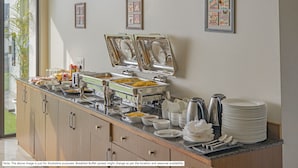 A breakfast buffet setup with various food items and utensils. - Treebo Saga Apartment (Bengaluru)