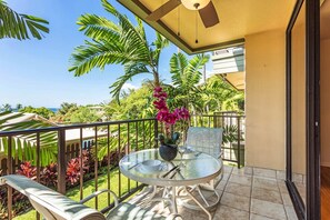 Ein Balkon mit Glastisch, Stühlen und einem Blumentopf.