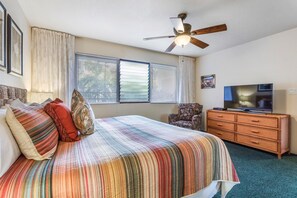 Ein Hotelzimmer mit Bett, Fernseher, Deckenventilator und einem Fenster mit Jalousien.