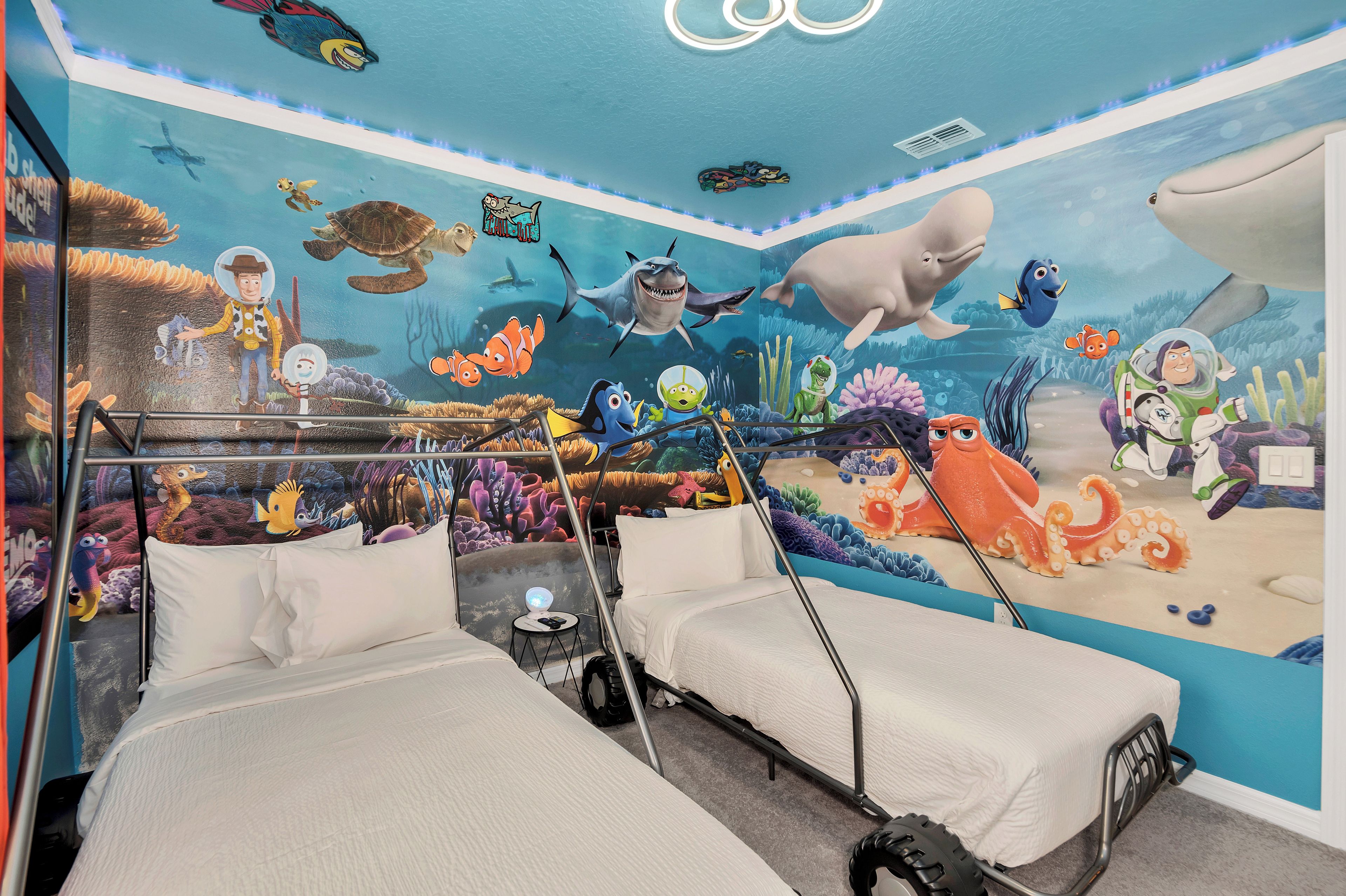 A bedroom with a mural of an underwater scene, two beds, and a small table.
