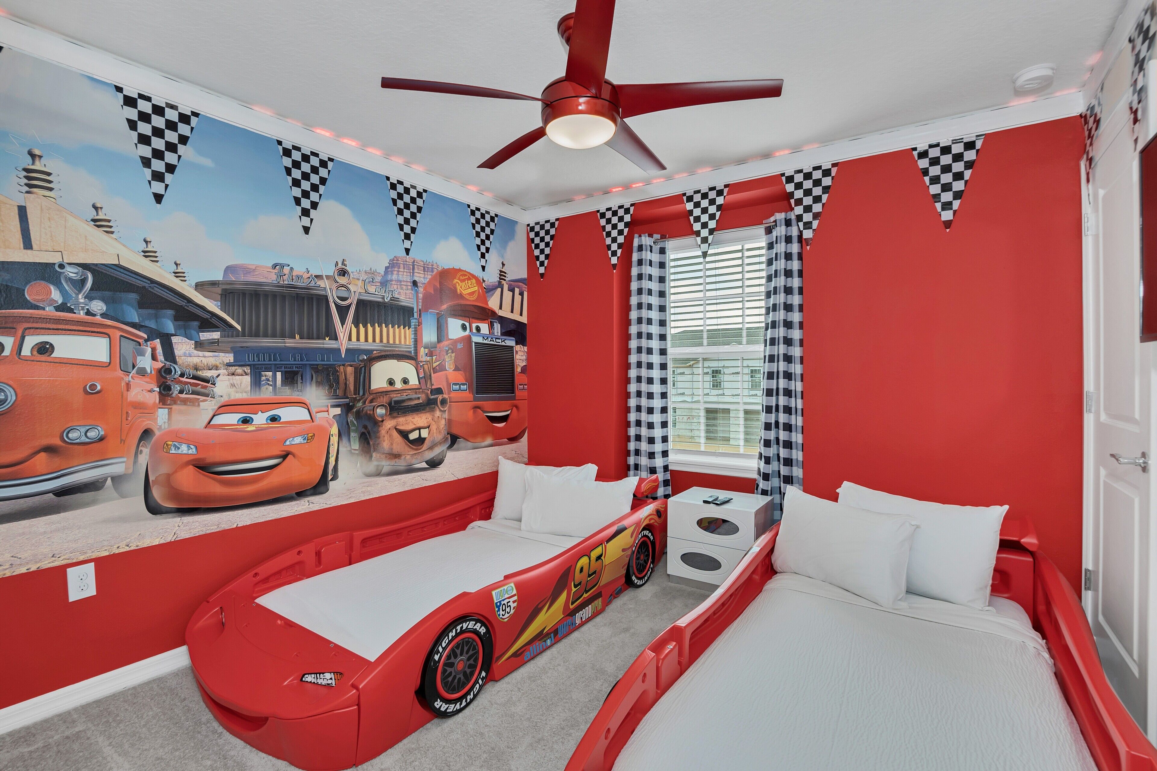 Ein Schlafzimmer im Rennwagen-Design mit Bett, Deckenventilator und Wandgemälde.