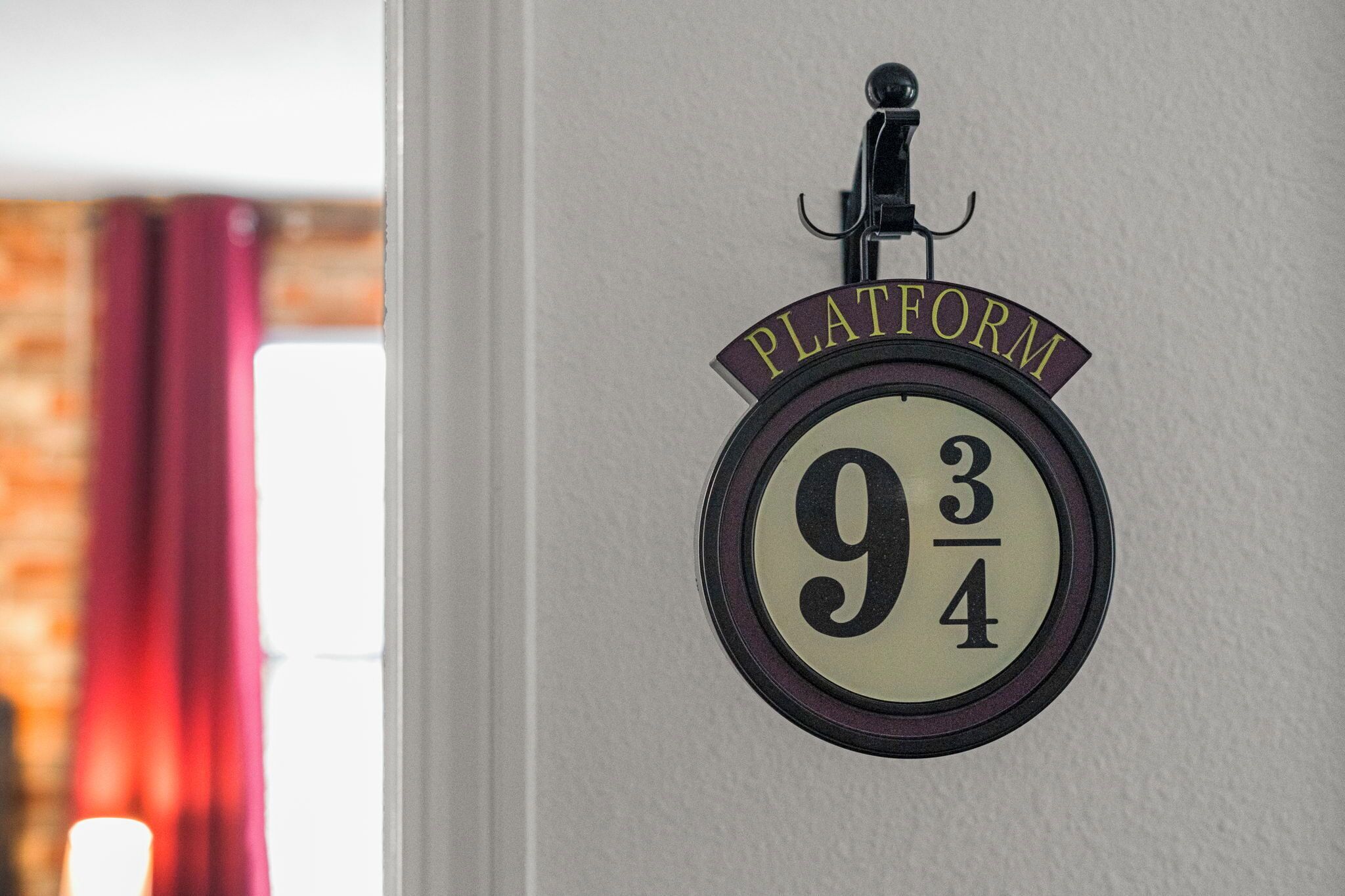 A wall-mounted sign with the text "PLATFORM 9 3/4" and a hook above it.