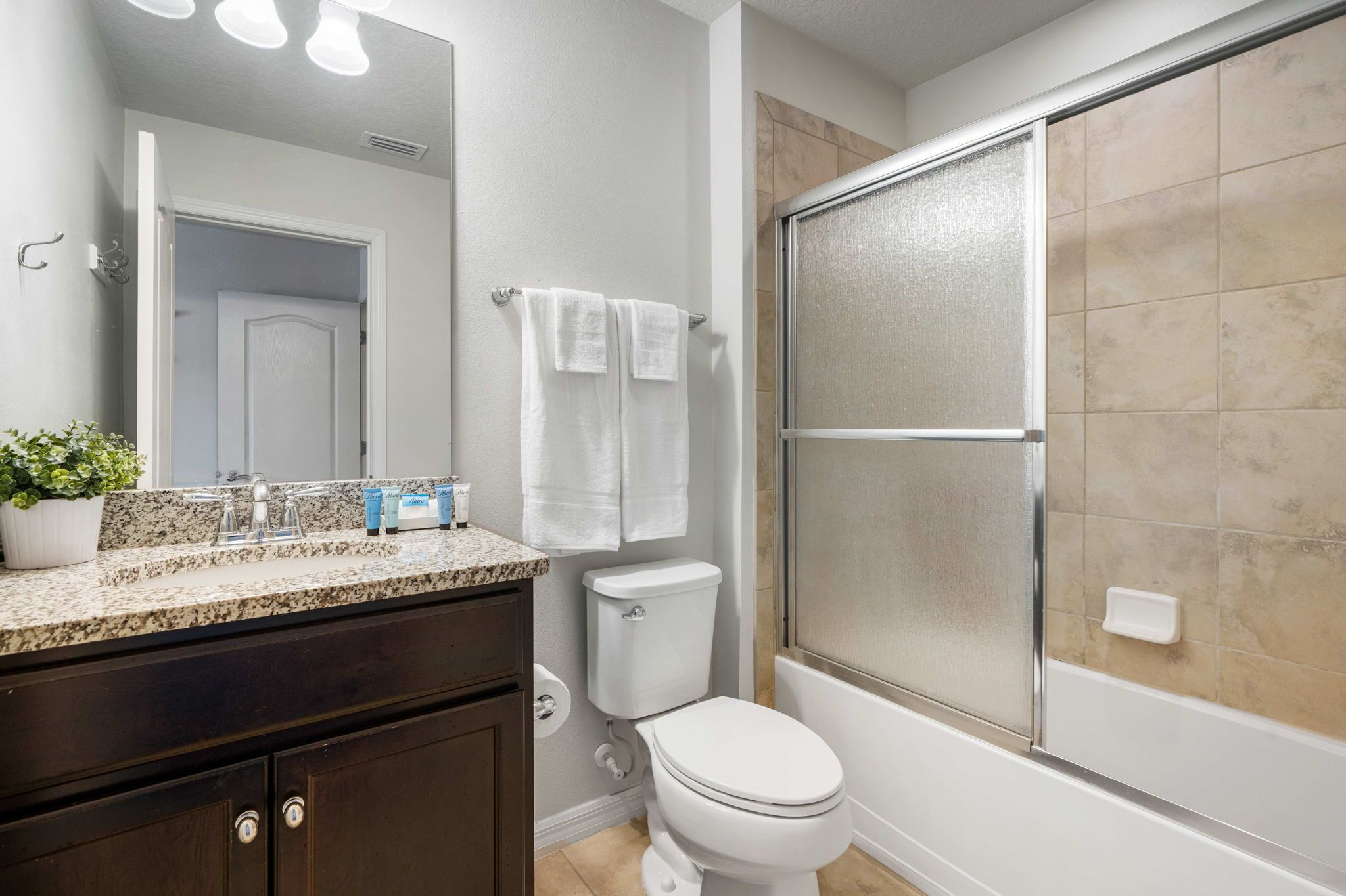 A bathroom with a toilet, sink, mirror, and shower.
