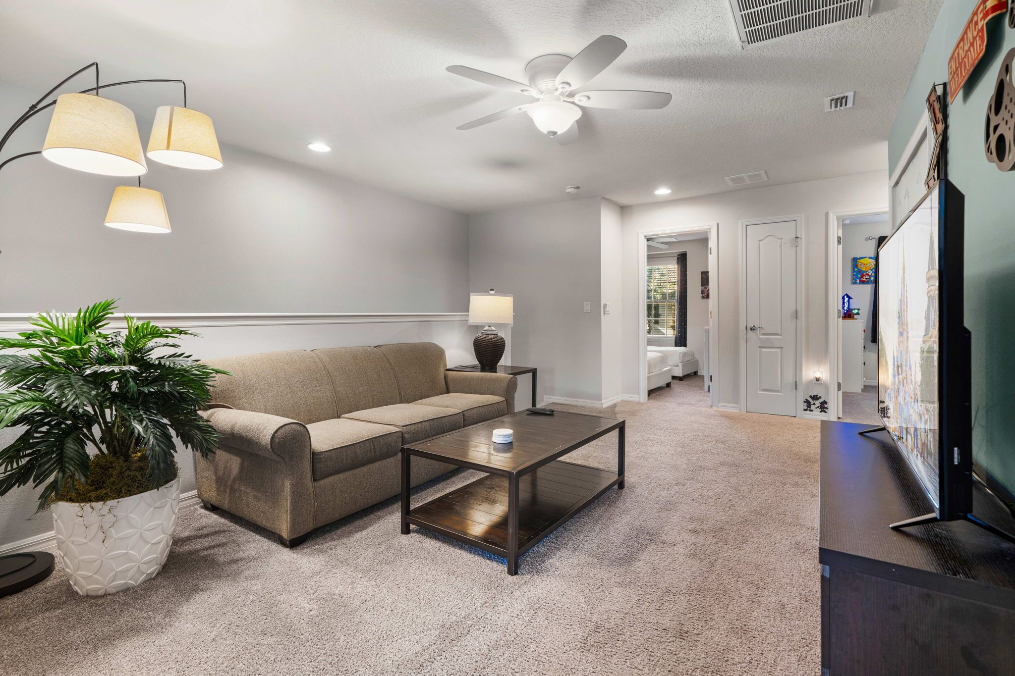 Ein Wohnzimmer mit Sofa, Couchtisch, Blumentopf, Deckenventilator und Wandlampe.