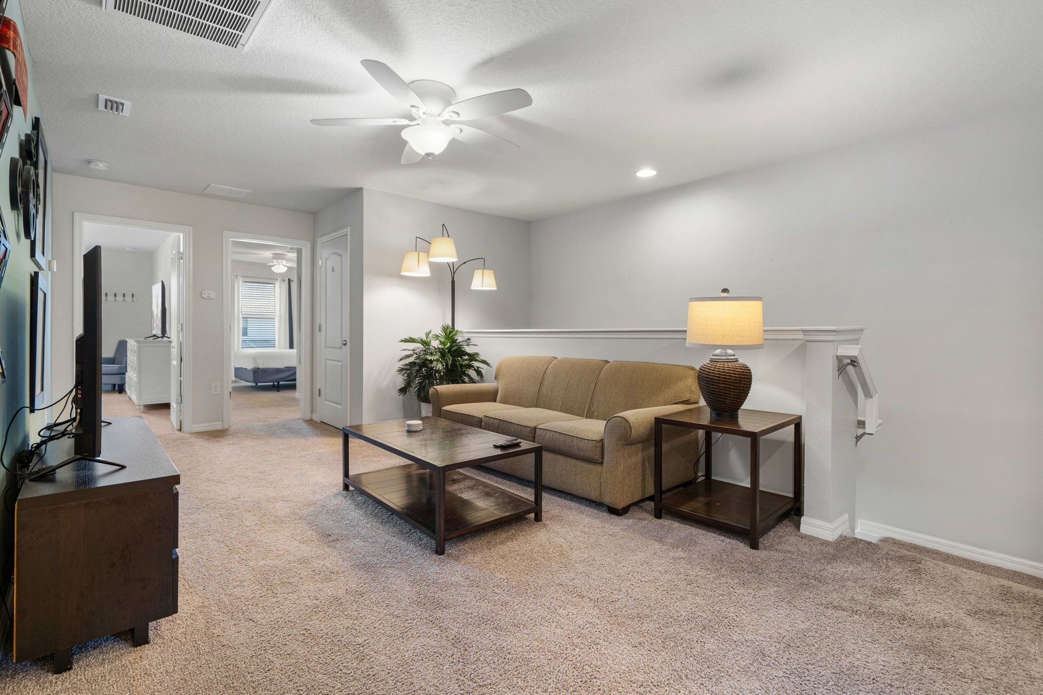 A living room with a ceiling fan, a sofa, a coffee table, and two floor lamps.