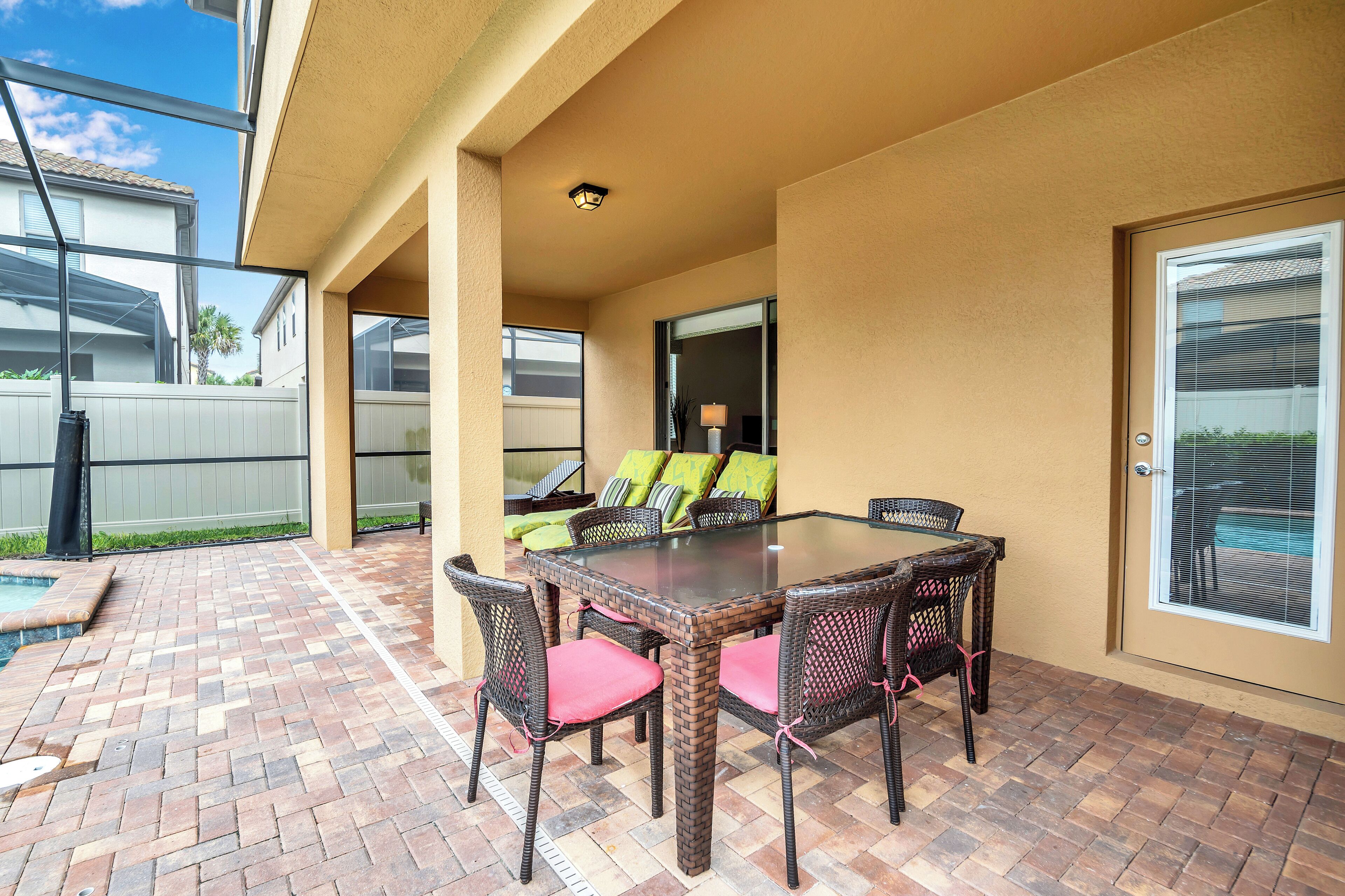 A patio with a glass-top table, wicker chairs, and a pool.