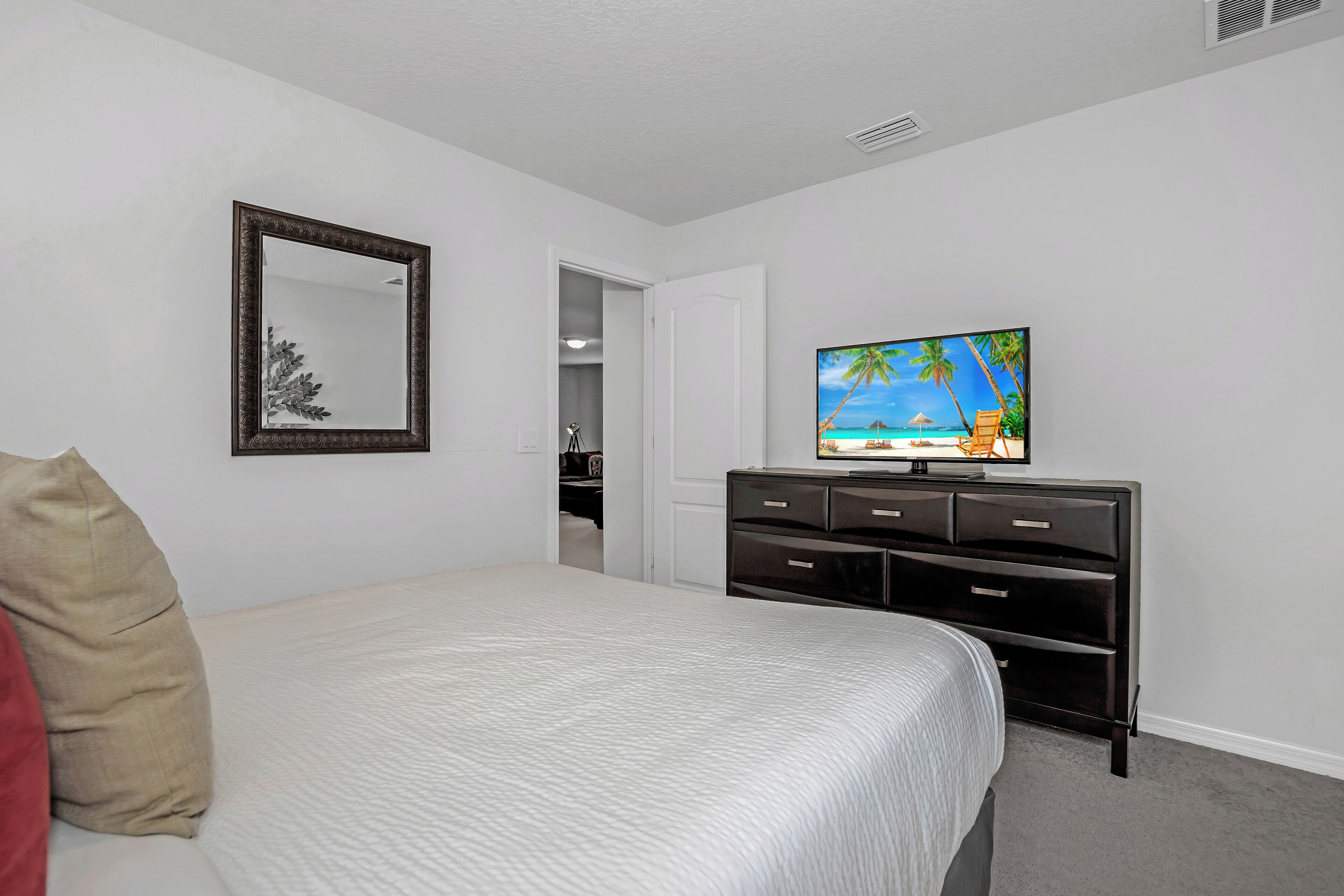 A hotel room with a bed, a TV on a dresser, a mirror, and a door leading to a closet.