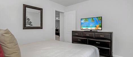 A hotel room with a bed, a TV on a dresser, a mirror, and a door leading to a closet.