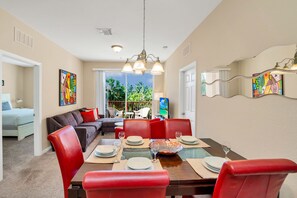 A dining area with a table set for four, red chairs, and a view of the outdoors.