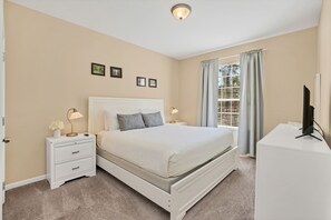 A bedroom with a bed, nightstands, a desk, and a television.