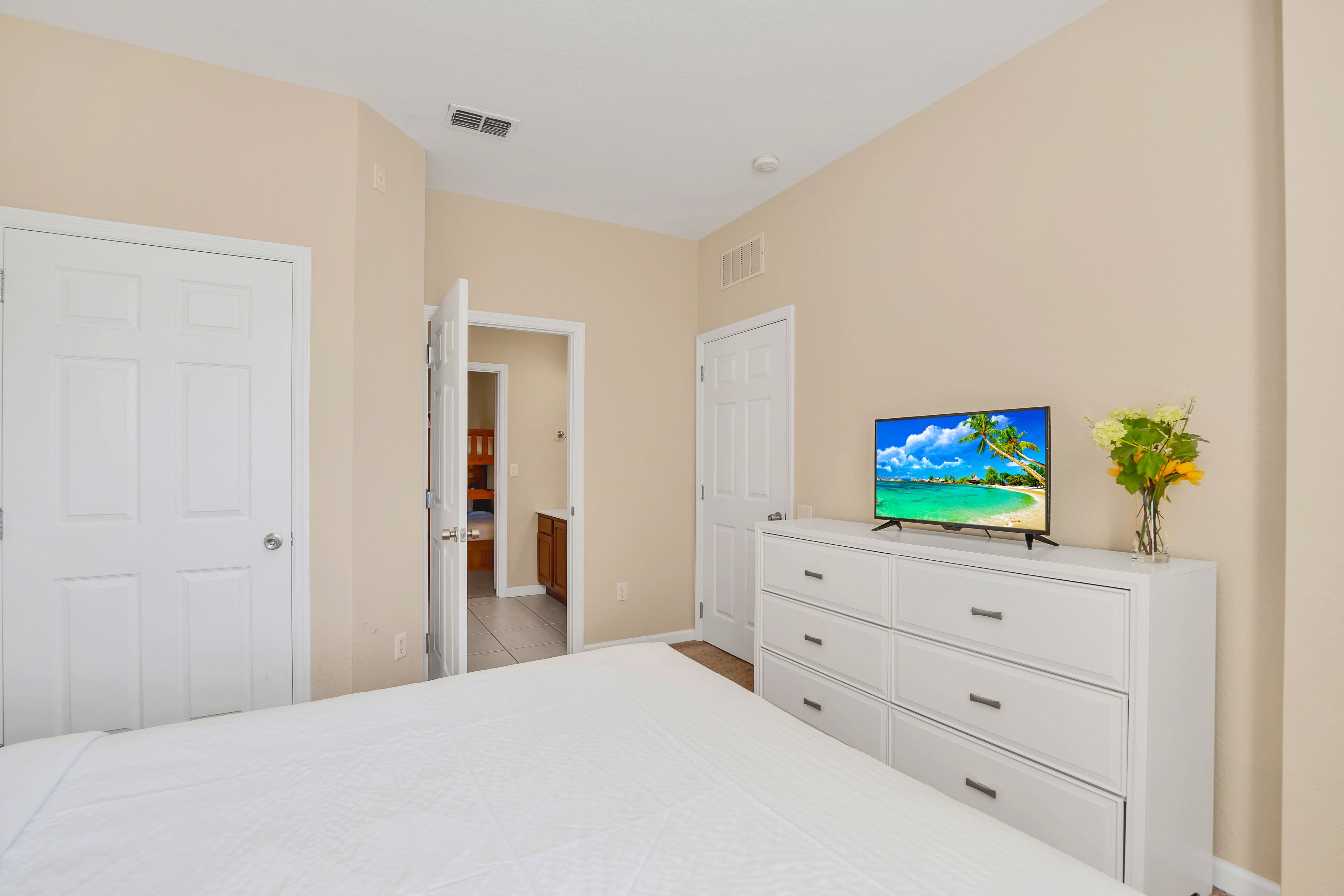 Un dormitorio con cama, cómoda y televisor sobre un mueble.