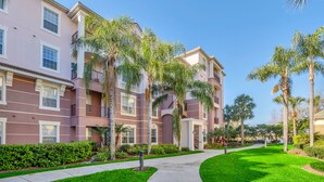 A multi-story residential building with balconies, a well-maintained lawn, and palm trees. - 4024 Breakview Drive #208 (Orlando)