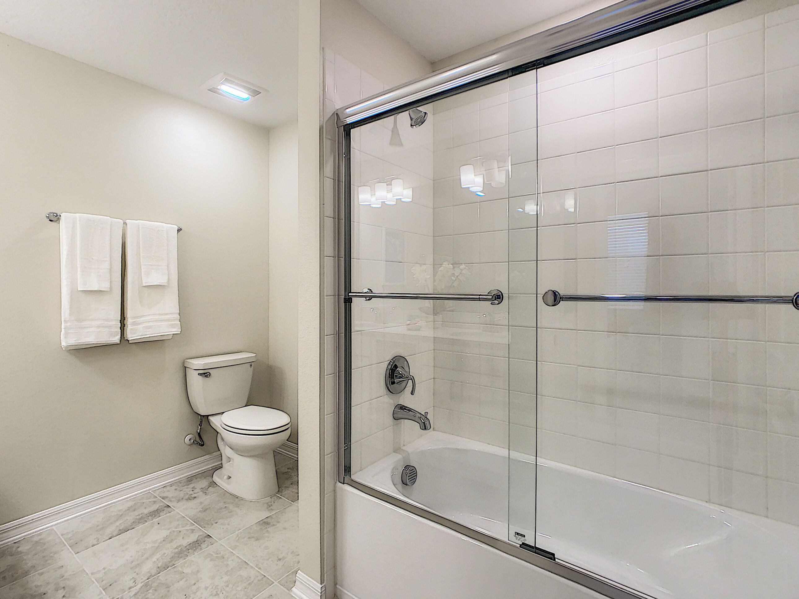 A modern bathroom with a glass-enclosed shower, a toilet, and a bathtub.