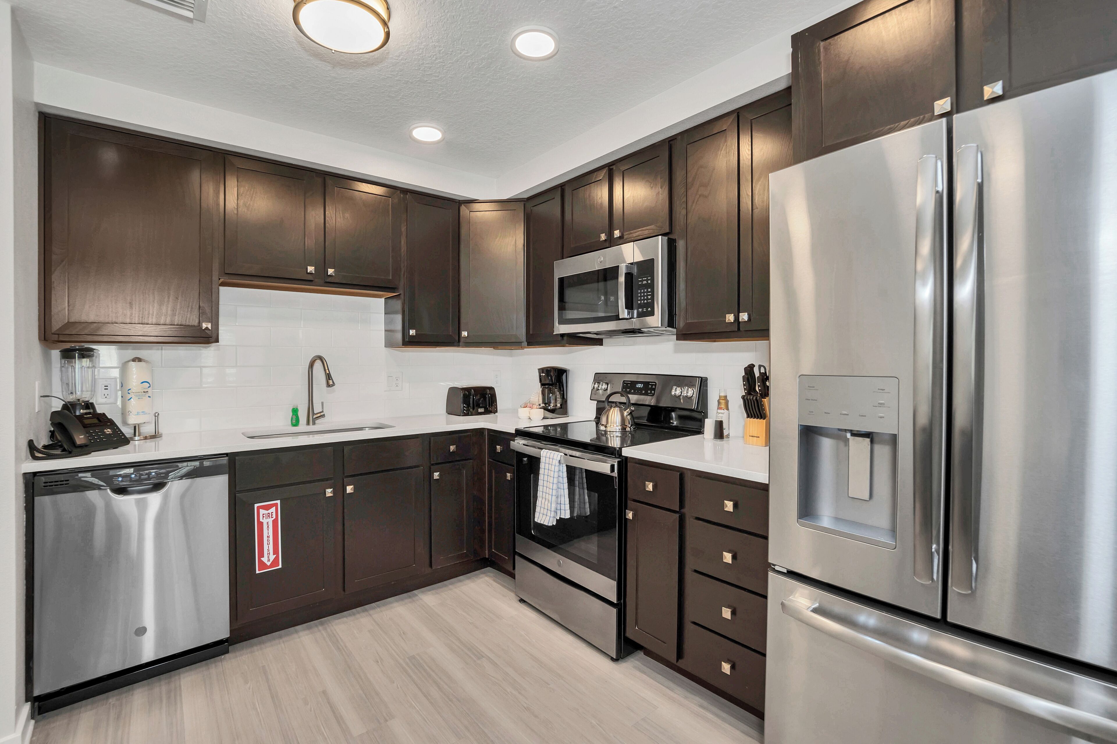 A modern kitchen with dark wood cabinets, stainless steel appliances, and a built-in water dispenser.