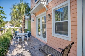 A patio with a table and chairs, a bench, and a house with a window and door. - 3078 Key Lime Loop (Kissimmee)