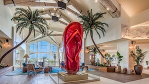 A spacious lobby with a large red sculpture, palm trees, and modern furnishings. - 3078 Key Lime Loop (Kissimmee)