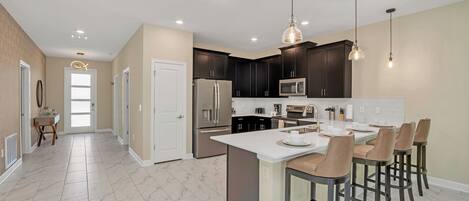 A modern kitchen with dark cabinets, a white island, and bar stools.