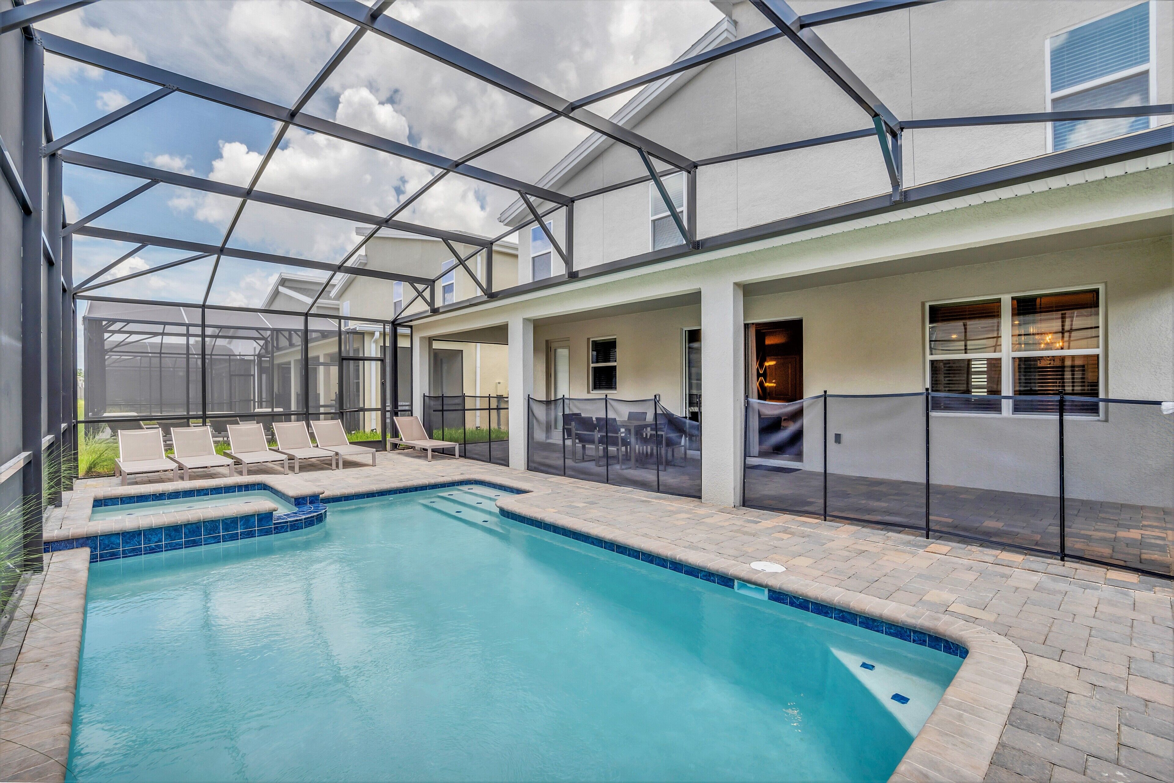A swimming pool with lounge chairs and a covered patio area.