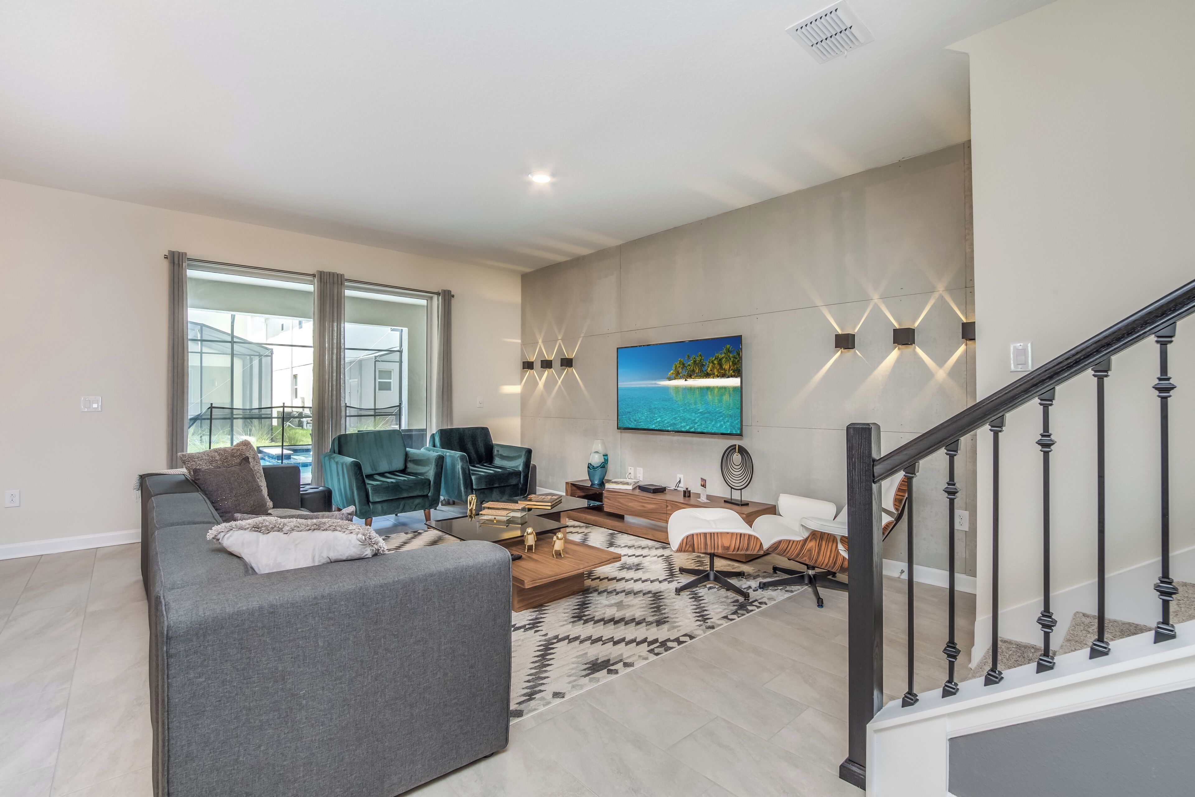 A modern living room with a grey sofa, a coffee table, and a TV mounted on the wall.