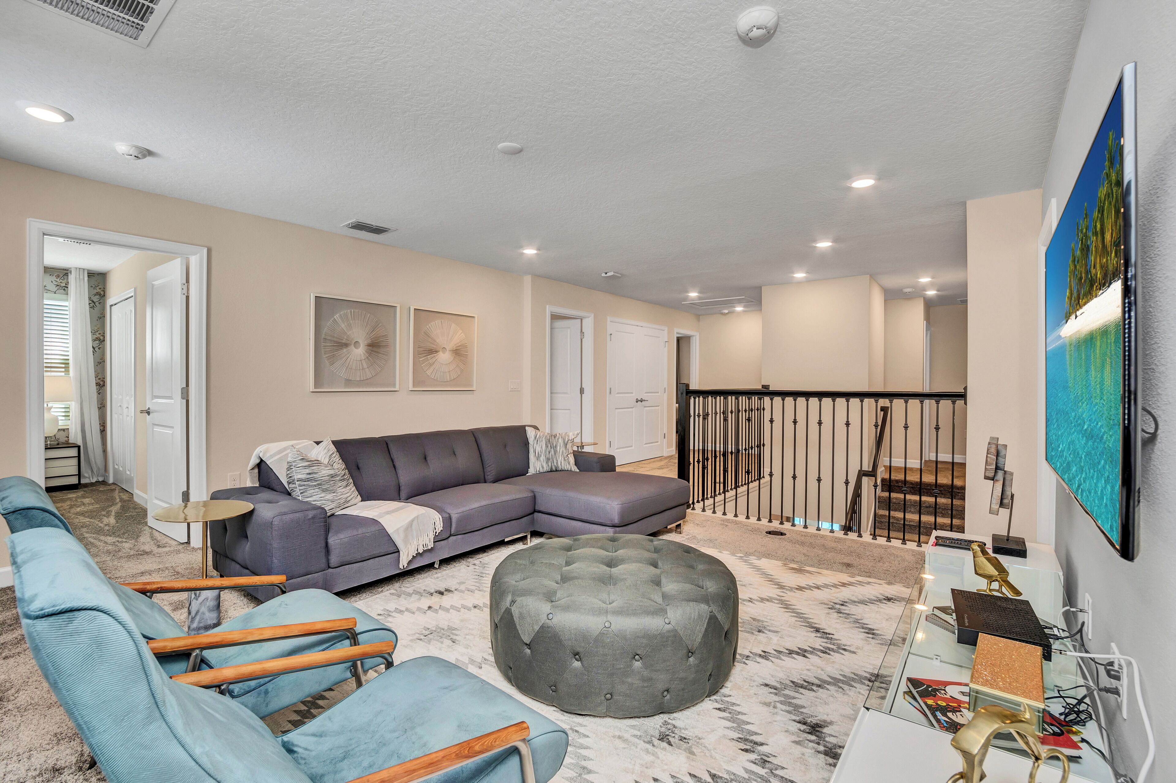 A modern living room with a sectional sofa, ottoman, and blue armchairs.