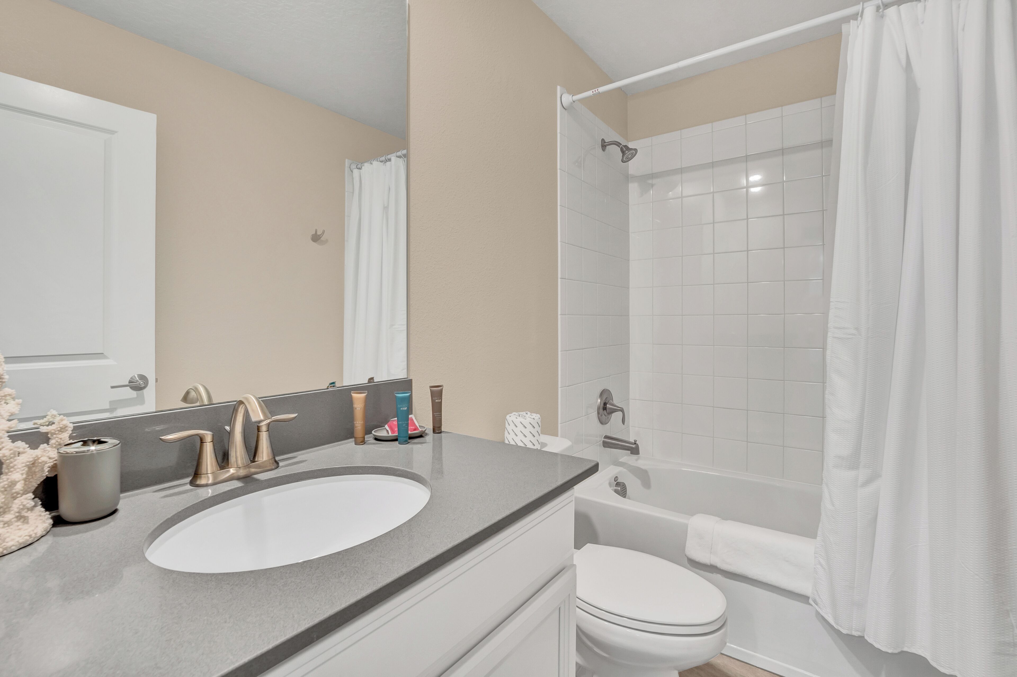 A bathroom with a sink, mirror, toilet, and shower.