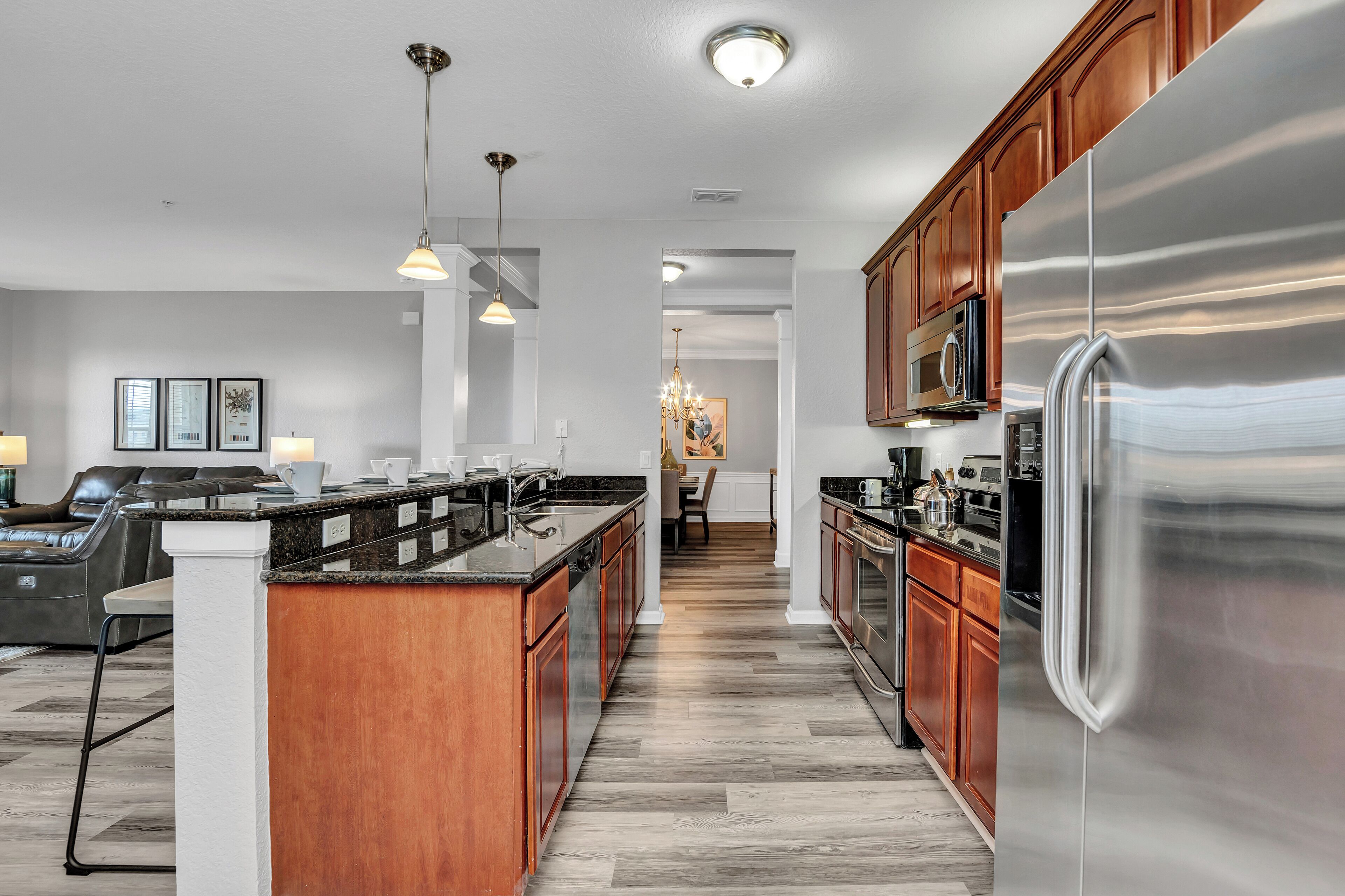 A modern kitchen with a large stainless steel refrigerator, wooden cabinets, and a central island with a sink.
