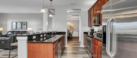 A modern kitchen with a large stainless steel refrigerator, wooden cabinets, and a central island with a sink.