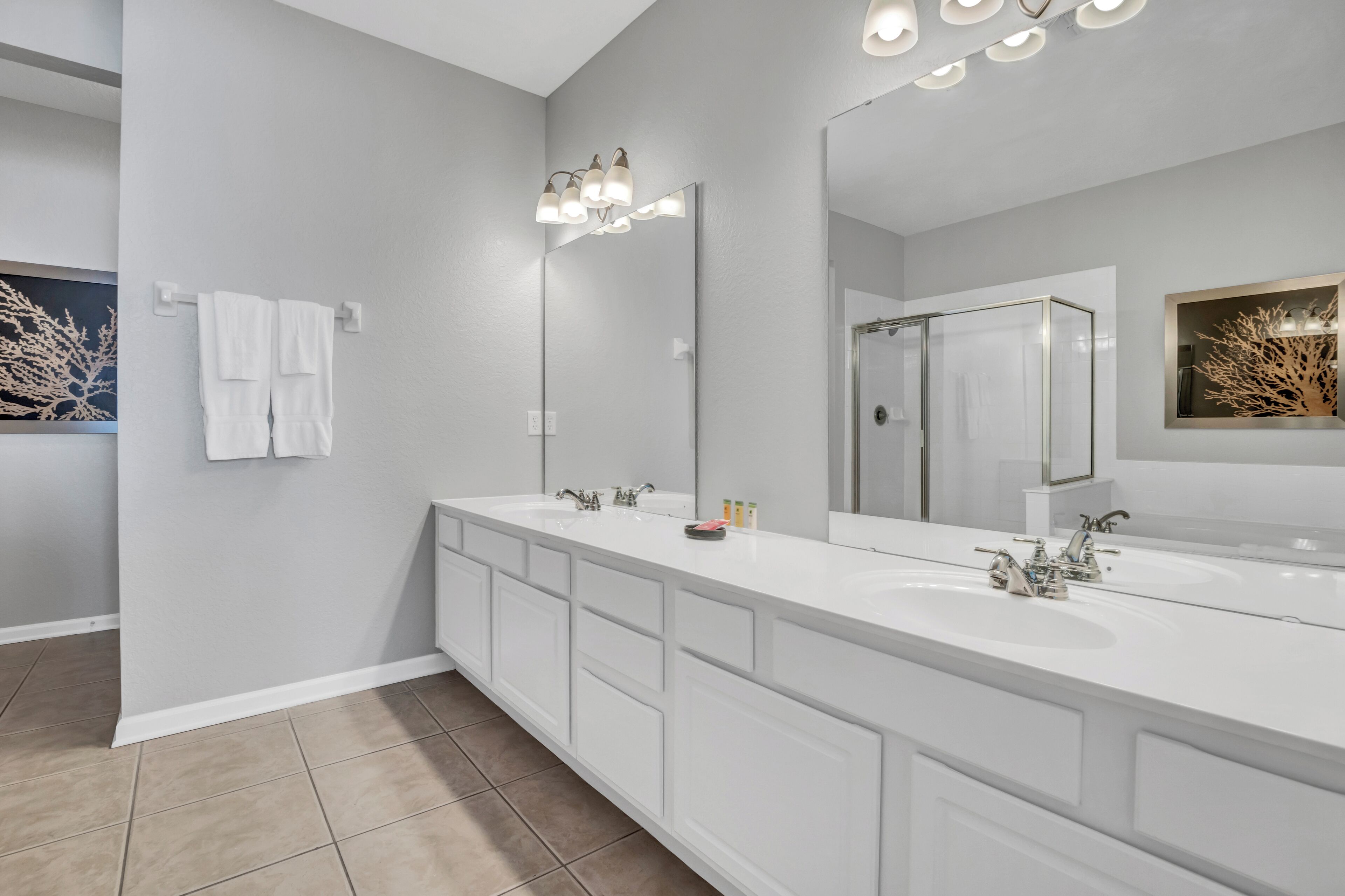 A modern bathroom with two sinks, a large mirror, and a shower area.