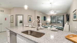 A modern kitchen with granite countertops, a stainless steel sink, and pendant lighting. - Luxurious Condo Near Disneyfree Waterpark Access (Kissimmee)