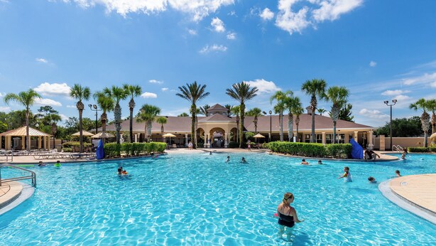A large outdoor swimming pool with multiple lanes, surrounded by palm trees and lounge chairs. - Luxurious Condo Near Disneyfree Waterpark Access (Kissimmee)