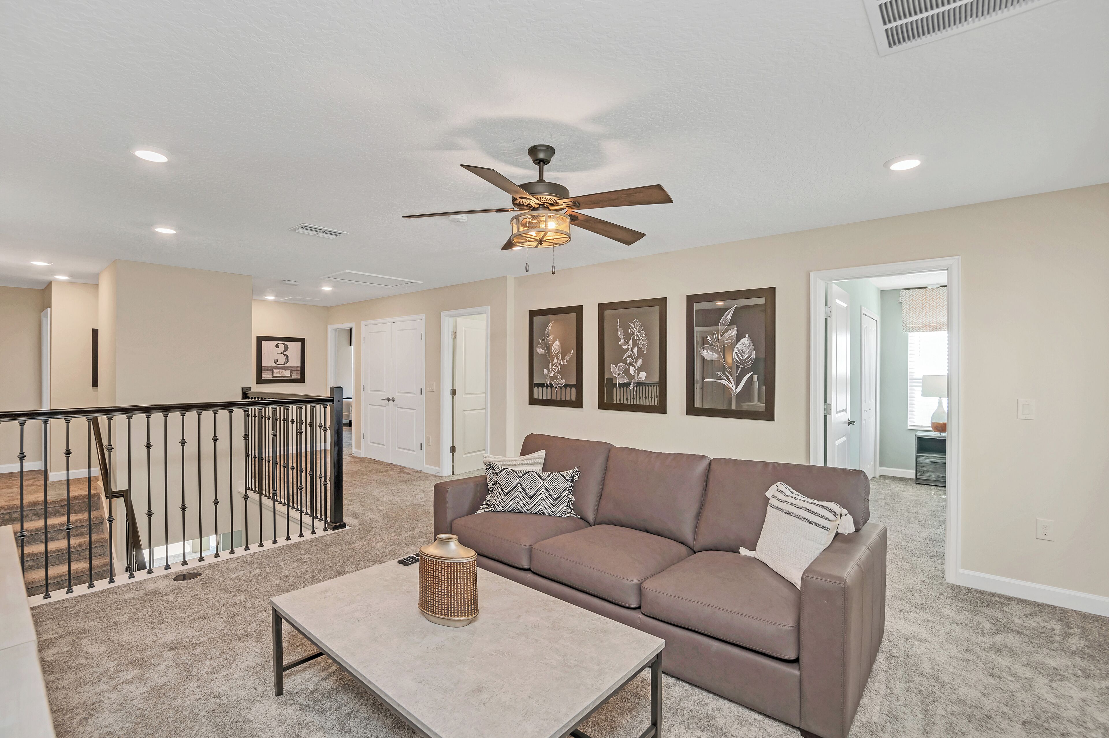 A spacious living room with a brown sofa, a coffee table, and a ceiling fan.