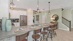 A spacious kitchen with a large island, modern appliances, and a bar area with stools. - Large Villa, Private Pool+game Room+movie Theater! (Kissimmee)