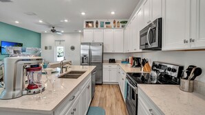 A modern kitchen with white cabinets, stainless steel appliances, and a marble countertop. - Large Margaritaville Villa w/ Private Pool + View (Kissimmee)