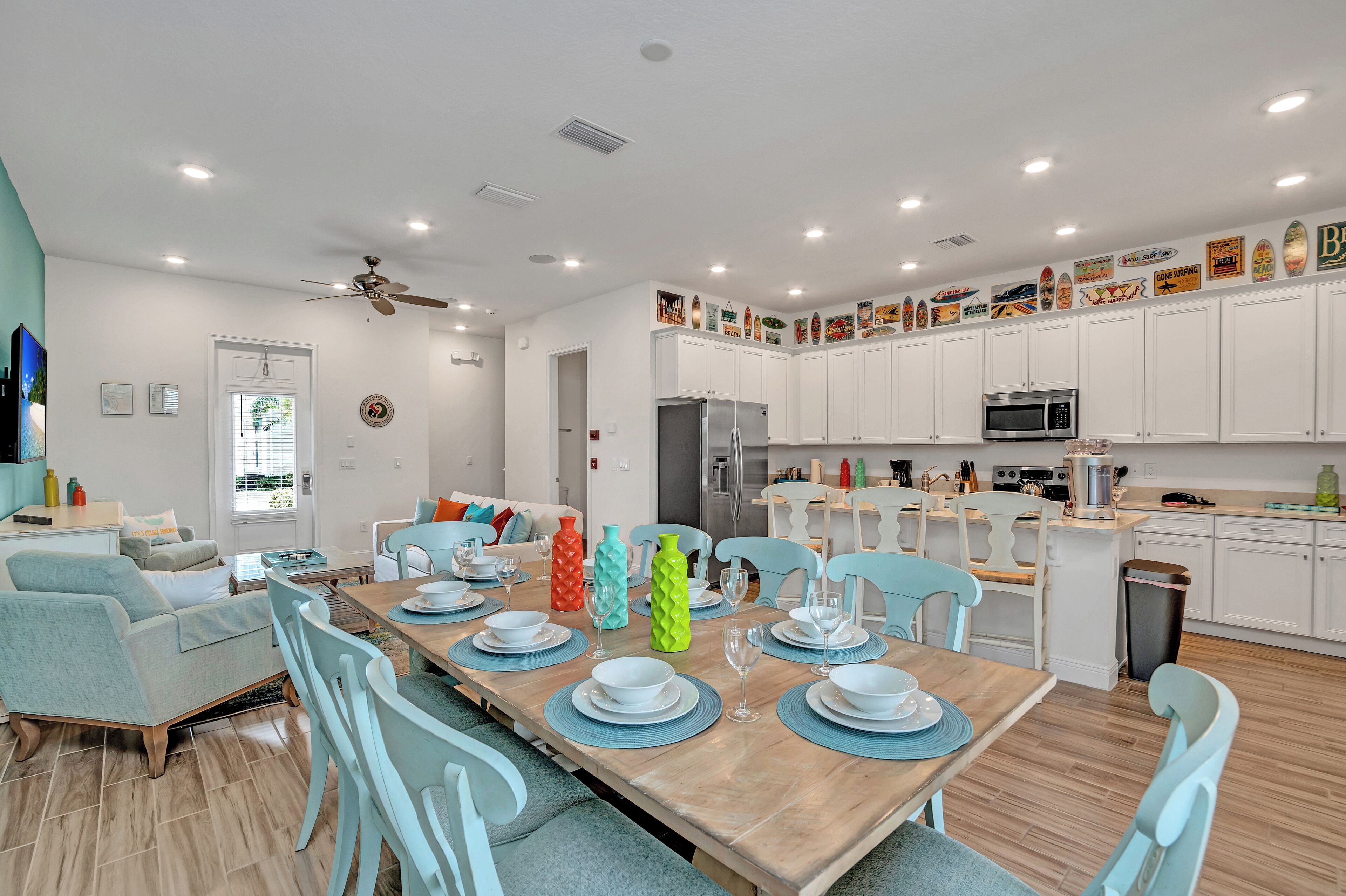 Una cocina moderna con armarios blancos, una isla central y un comedor con una mesa de madera dispuesta para seis comensales.