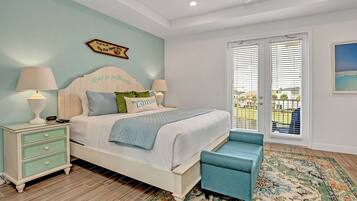 A bedroom with a bed, bedside tables, a bench, a patterned rug, and a balcony with a view.