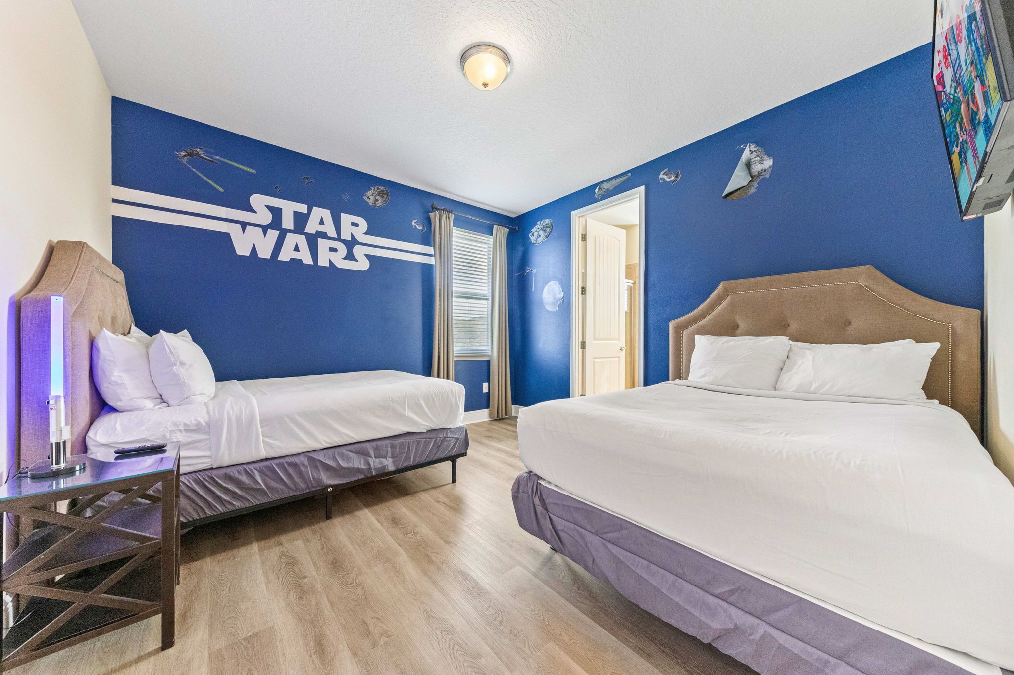 A room with two beds, a desk, and Star Wars-themed wall decals.