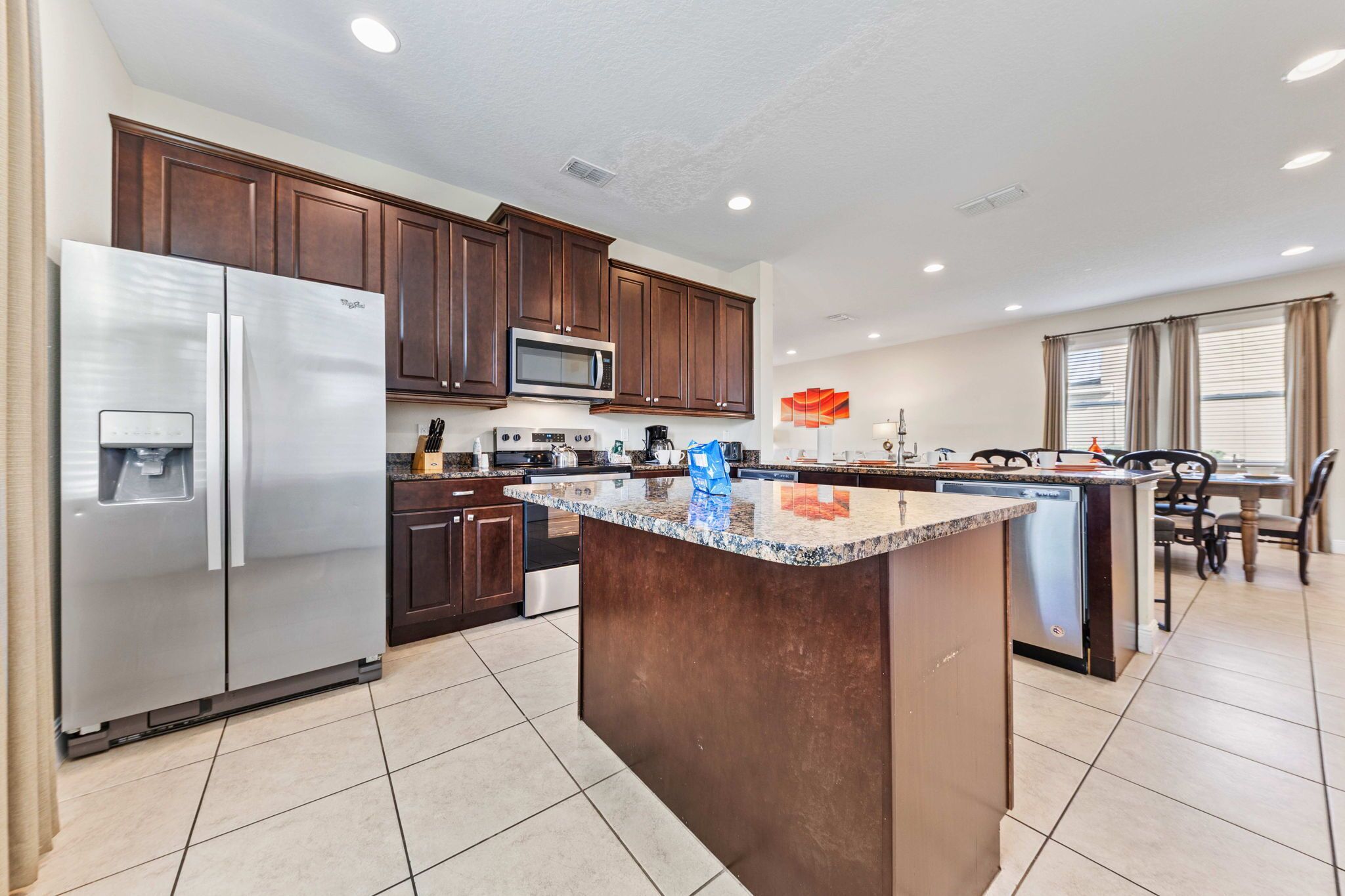 A modern kitchen with dark wood cabinets, stainless steel appliances, and a granite countertop island.