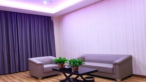 A modern living room with a sofa, a coffee table, and two potted plants. - Chonpines Hotel (Zhengzhou)