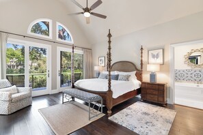 Ein geräumiges Schlafzimmer mit einem Himmelbett, einer Sitzecke mit einer Bank und durch große Schiebetüren Zugang zu einem Balkon.