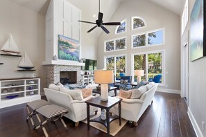 A spacious living room with a fireplace, white sofas, a coffee table, and a ceiling fan. - Stunning, spacious renovation in the heart of Kiawah (Johns Island)
