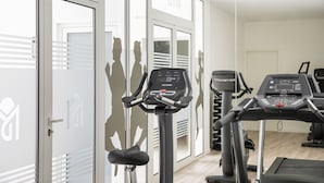 Un gimnasio con equipo de ejercicio, incluyendo cintas de correr y bicicletas estáticas, y una puerta con la leyenda 'GYM'.