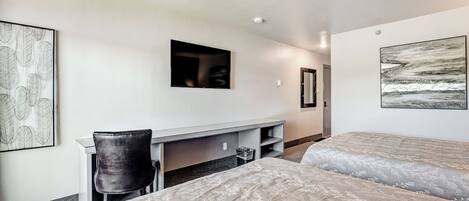 Une chambre d’hôtel avec deux lits, un bureau et une chaise. Les murs sont ornés d’œuvres d’art et le plafond est éclairé par un luminaire.