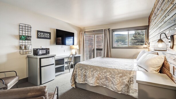Une chambre d’hôtel comprenant un lit, un bureau avec un micro-ondes, une télévision et une fenêtre avec des rideaux.