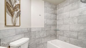 Une salle de bain moderne équipée de toilettes, d’un lavabo et d’une baignoire.