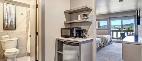 Una habitación de hotel compacta con baño, kitchenette y un balcón con vistas.