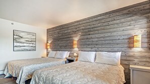 Une chambre d’hôtel avec deux lits, une tête de lit en bois, des lampes fixées au mur et un tableau encadré.