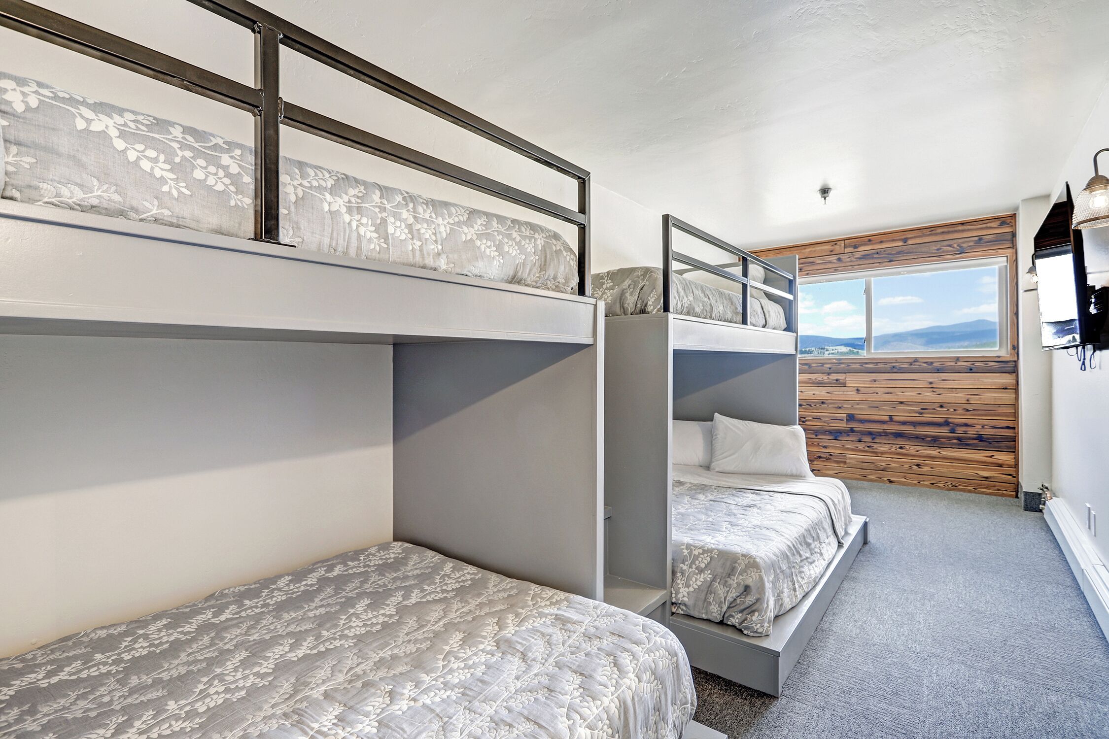 A bunk bed room with a view of the mountains through a large window.