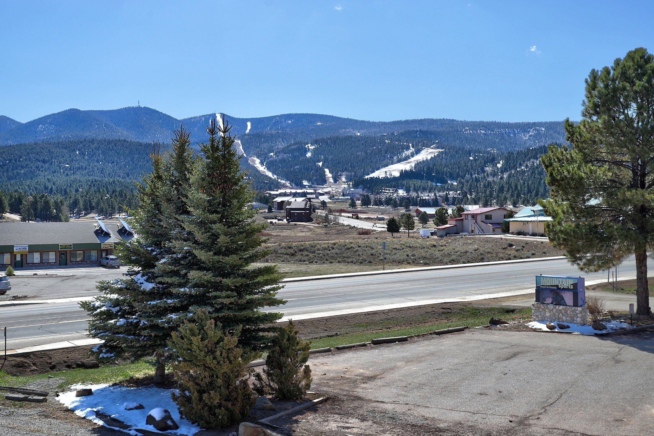 A road with a snow-covered landscape and a mountain in the background.